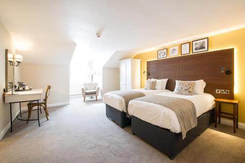 a hotel room with two beds and a desk at The Snowy Owl by Innkeeper's Collection in Cramlington