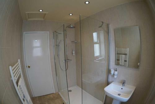 a bathroom with a shower and a sink at Bryn-Y-Mor (ADULT ONLY) in Llandudno