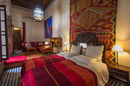 a bedroom with a large bed with a colorful wall at Riad Dar Cordoba in Fez