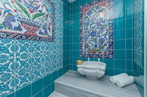a bathroom with blue tiled walls and a white sink at Darussaade Hotel Old City - Sultanahmet in Istanbul