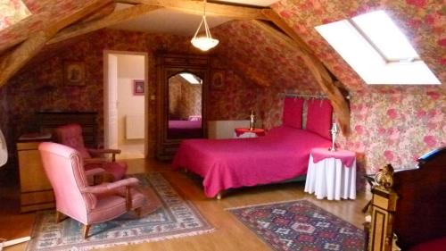 a bedroom with a pink bed and a chair at Domaine de la Houzardiere in Bazougers