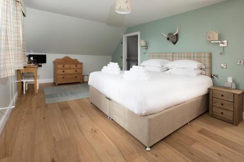 a bedroom with a large bed with white sheets and pillows at Blairmore Farm in Crieff