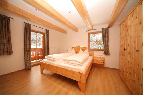 a bedroom with a bed and two windows at Die Postlehen-Alm in Schladming