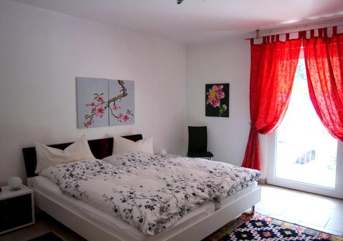 Schlafzimmer mit einem Bett mit roten Vorhängen und einem Fenster in der Unterkunft Ferienwohnung-Mosel in Traben-Trarbach