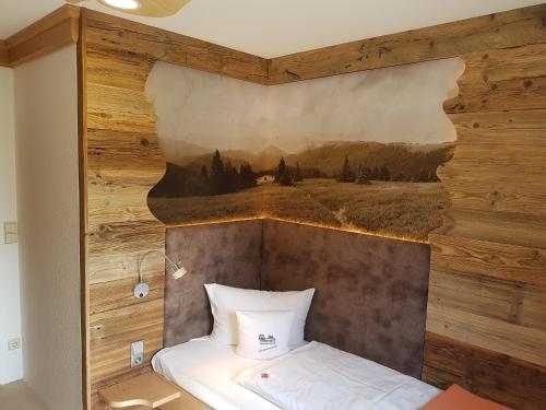 a bed in a room with a painting on the wall at Hotel und Restaurant Köhlerhütte - Fürstenbrunn in Grünhain-Beierfeld