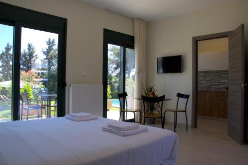 a bedroom with a bed with white sheets and a balcony at Angelbay Bungalows in Agia Triada