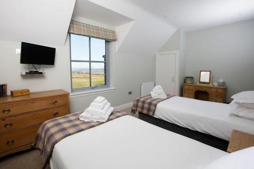 a bedroom with two beds and a tv and a window at Blairmore Farm in Crieff
