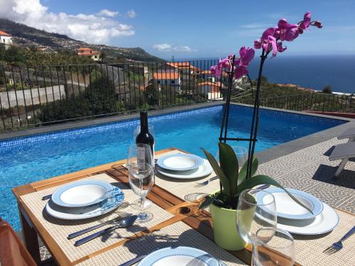 a dining table with a bottle of wine and a pool at Vila do Rocha in Calheta