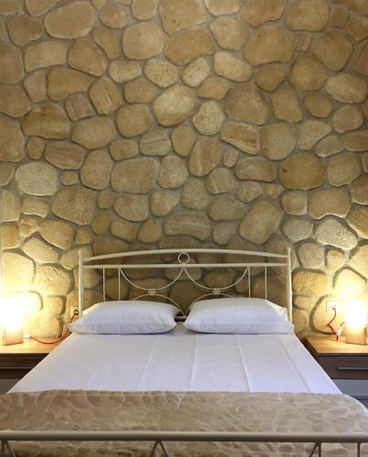 a bed in a room with a stone wall at Amfithea House in Siviri