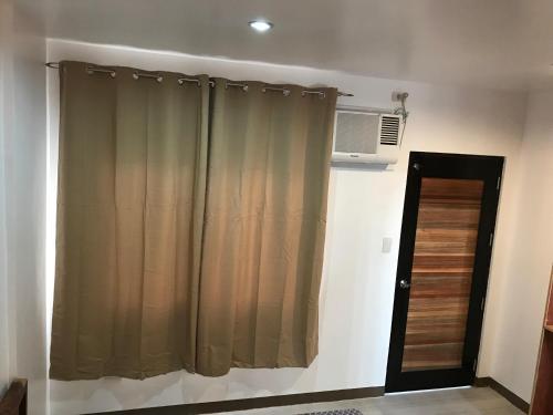 a room with a curtain and a window with a fan at Seabreeze Beach Lodge in Nasugbu