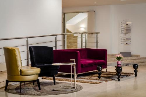 a living room with two chairs and a red couch at Eurostars Roma Aeterna in Rome