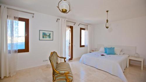 a white bedroom with a bed and a chair at Stunning Seaviews in Kalkan