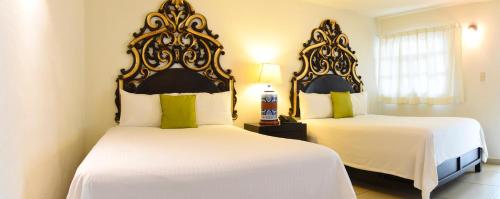 a bedroom with two beds with white sheets at Hotel Expres By Hosting House in Morelia