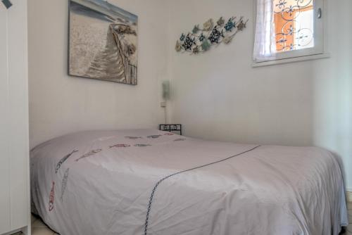een wit bed in een kamer met twee foto's aan de muur bij Appartement Le Flamant Rose in Port-la-Nouvelle