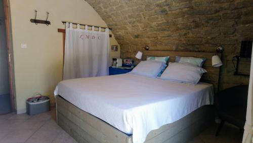een slaapkamer met een groot bed en een bakstenen muur bij La Méridienne des Collines in La Motte-de-Galaure