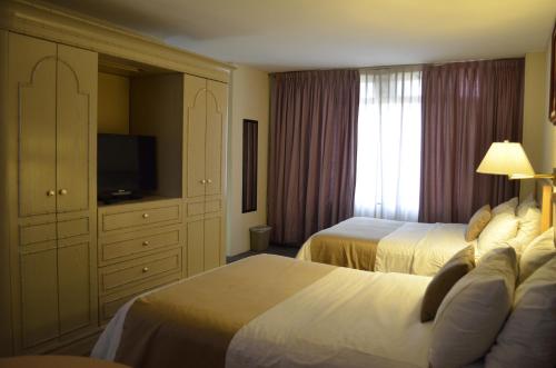 a hotel room with two beds and a television at Best Western PLUS Plaza Florida & Tower in Irapuato