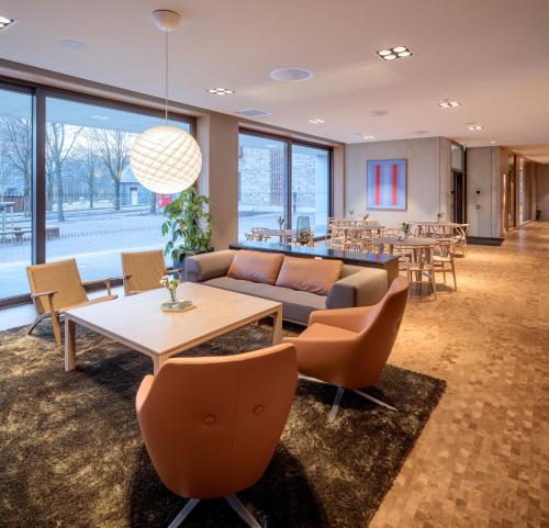 a living room with a couch and tables and chairs at Ydalir Hotel in Stavanger