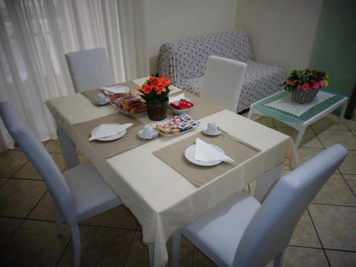 een eettafel met stoelen en een witte tafel met bloemen erop bij A Dream B&B Napoli in Napels