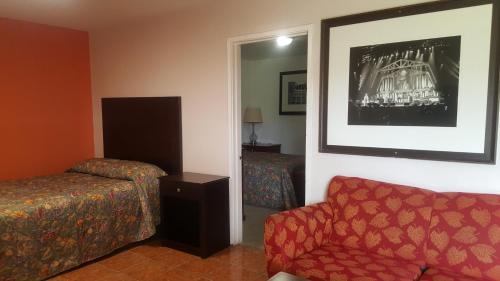 Habitación de hotel con sofá, cama y espejo en Monte Carlo Motel, en Nueva Orleans