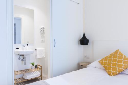 1 dormitorio con cama blanca y lavamanos en Pensión Buenpas en San Sebastián