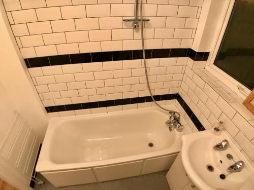 a white tub and a sink in a bathroom at Central apartment 5 mins Putney tube station in London