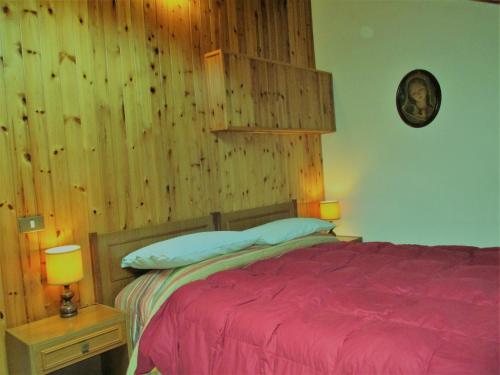 ein Schlafzimmer mit einem roten Bett mit einer Holzwand in der Unterkunft Appartamento il Bosco in Pievepelago