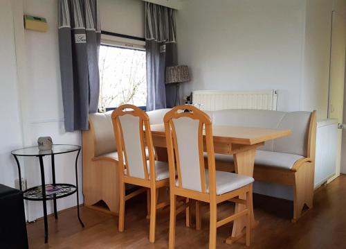 a dining room table with two chairs and a table and a couch at Corona Laboris in Colijnsplaat