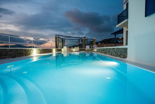 a large swimming pool with blue water at night at Mykonos Welcome Suites in Ano Mera