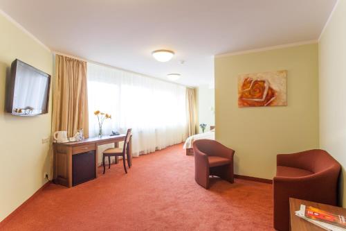 a hotel room with a desk and a bed and a television at AirInn Vilnius Hotel in Vilnius