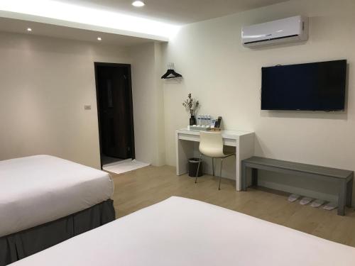 a hotel room with a bed and a desk and a television at 800 Lan Homestay in Zhushan