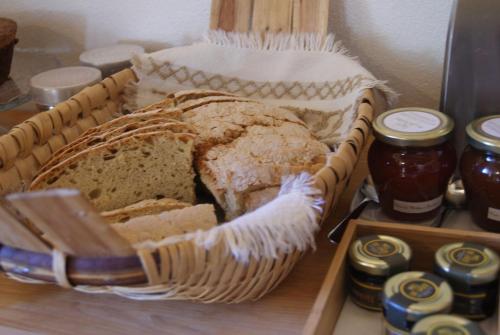 Una cesta de pan sobre una mesa con tarros de conservas en Casa De Santo Antão - Turismo Rural, en Padrões
