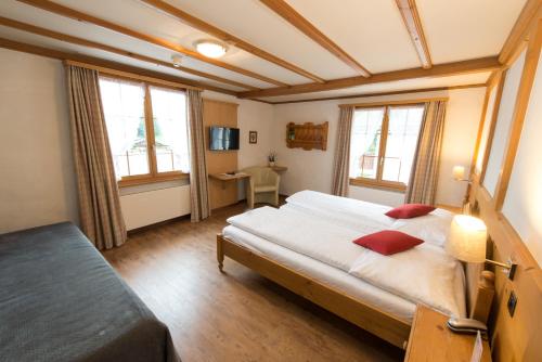 a bedroom with a large bed and two windows at Sporthotel Victoria in Gstaad