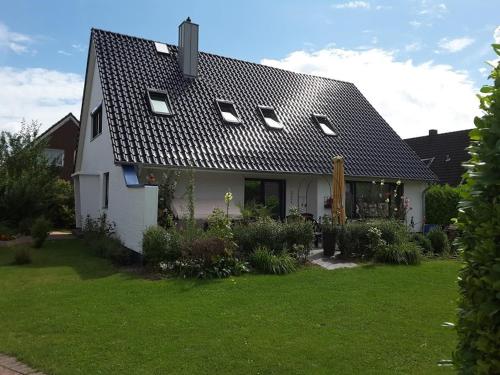 a white house with a black roof on a yard at Haus Ostseestrand36 in Timmendorfer Strand