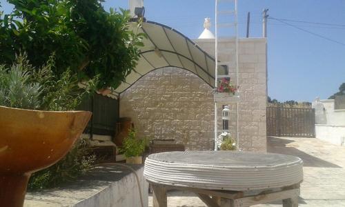 a bench sitting in front of a building with an umbrella at Trullo Le Tre Sorelle in Cisternino