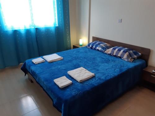 Un dormitorio con una cama azul con toallas. en Vasilas Holiday Apartment #1, en Lárnaca