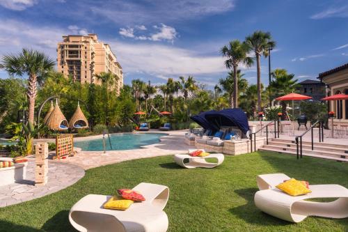 a pool at a resort with white chairs on the grass at Four Seasons Resort Orlando at Walt Disney World Resort in Orlando
