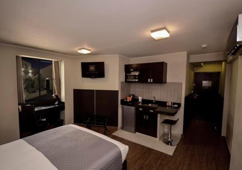 a bedroom with a bed and a kitchen with a sink at qp Hotels Arequipa in Arequipa