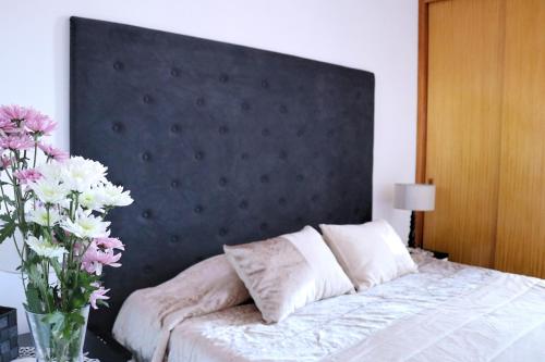 a bed with a black headboard and a vase of flowers at Mericia's Gorgeous View in Funchal