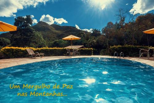 une grande piscine avec chaises et parasols dans l'établissement Pousada Villa Lagoa das Cores, à Vale do Capão