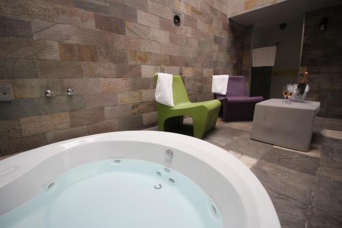 a bathroom with a tub and a chair and a table at Snob Motel (Adult Only) in Belo Horizonte