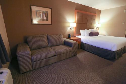 a hotel room with a bed and a chair at Days Inn by Wyndham Calgary Airport in Calgary