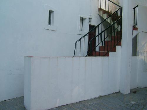 a white wall with a staircase next to a building at Casa de Férias in Monchique