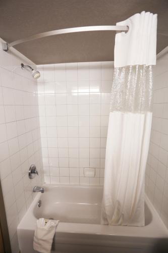 a bathroom with a bath tub with a shower curtain at Days Inn by Wyndham Calgary Airport in Calgary