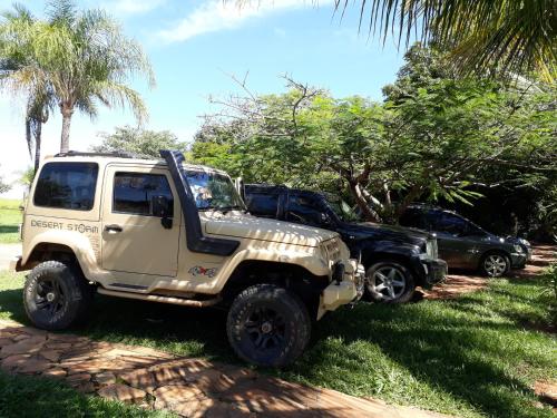 a white jeep parked in the grass next to two cars at Pousada da Lua in Delfinópolis