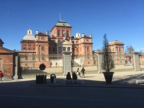 two people sitting on a bench in front of a large building at Casa Salice in Racconigi