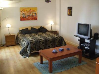 Un dormitorio con una cama, un televisor y una mesa. en Oro Plaza Apartamentos, en Buenos Aires