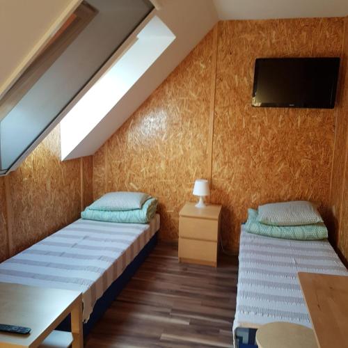 a room with two beds and a tv on the wall at Noclegi na Zaciszu in Kąty Rybackie