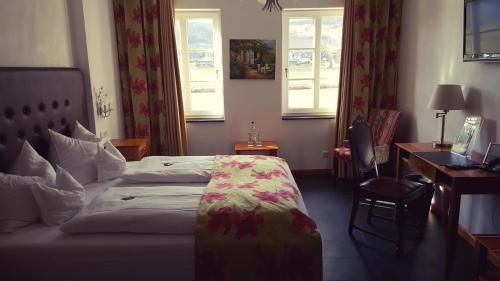 a hotel room with a bed and a desk and windows at Villa Beilstein in Beilstein