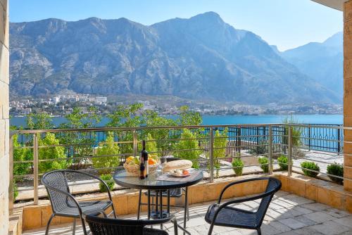 a table and chairs on a balcony with a view of the mountains at Apartments Residence Portofino in Kotor