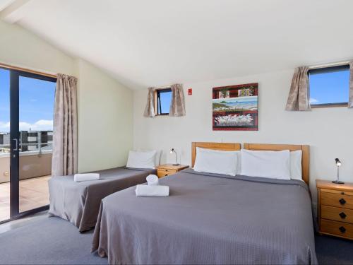 a bedroom with two beds and a balcony at Boatshed Motel Apartments in Mount Maunganui